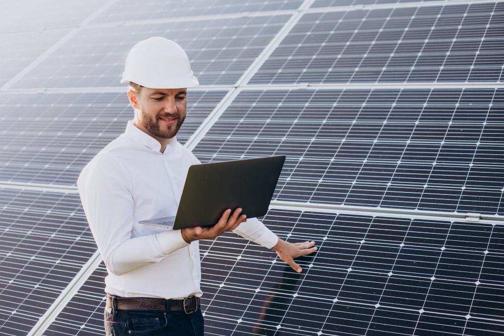 Napelemparkban dolgozó mérnök laptoppal, vállalati energetikai fejlesztés tervezése a Jedlik Ányos Energetikai Program keretében